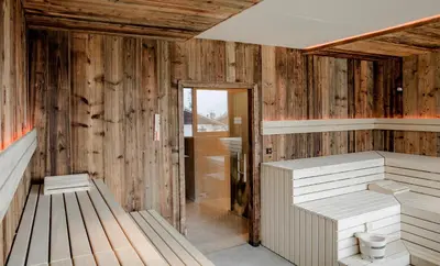 a sauna with two benches in a room with wooden walls at Hotel Fürstenhof in Schenna