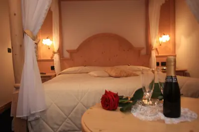 a bedroom with a bed and a table with a bottle of wine at Garnì Val de Costa in Canazei