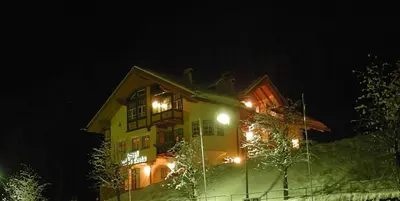 a house with lights on the side of it at night at Garnì Val de Costa in Canazei