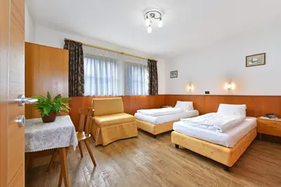 a hotel room with two beds and a chair at Villa Sole in San Vigilio Di Marebbe