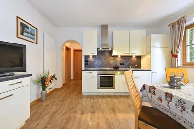 a kitchen with white cabinets and a table and a television at Villa Sole in San Vigilio Di Marebbe