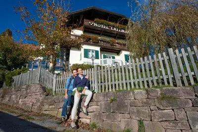 two people sitting on a fence in front of a house at Hotel Latemar in Soprabolzano