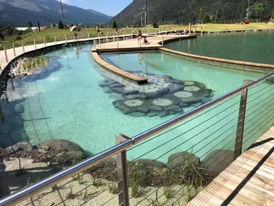 a large pool of blue water with a bridge at Residence Kristall- Fiemme Holidays in Predazzo