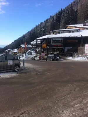 a parking lot with cars parked in front of a building at Casa a piè di pista in Tesero