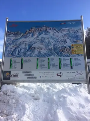 a sign in the snow with a mountain in the background at Casa a piè di pista in Tesero