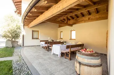 a patio with a table and chairs and a wooden ceiling at Weingut Donà in Appiano sulla Strada del Vino