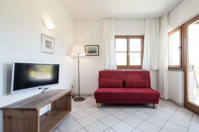 a living room with a red chair and a flat screen tv at Weingut Donà in Appiano sulla Strada del Vino