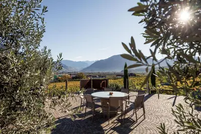 a table and chairs on a patio with mountains in the background at Weingut Donà in Appiano sulla Strada del Vino