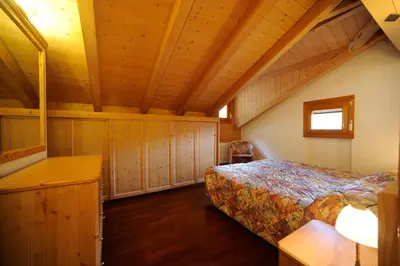 a bedroom with a bed and wooden ceilings at Residence Lagorai - Fiemme Holidays in Predazzo