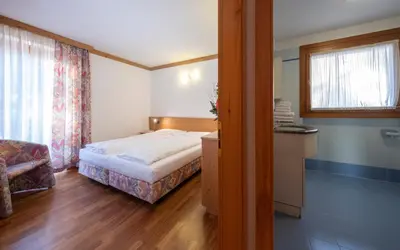 a small bedroom with a bed and a window at Residence Lagorai - Fiemme Holidays in Predazzo