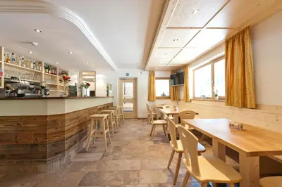 a restaurant with wooden tables and chairs and a bar at Gasthof Zur Sonne in Cardano