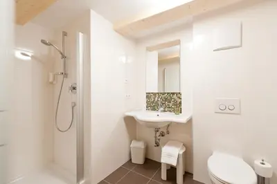 a white bathroom with a sink and a shower at Gasthof Zur Sonne in Cardano