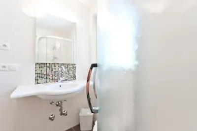 a white bathroom with a sink and a mirror at Gasthof Zur Sonne in Cardano