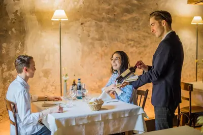 a man is holding a bottle of wine at a table at rössl bianco b&b&b in Merano