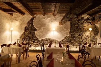 a dining room with tables and a stone wall at rössl bianco b&b&b in Merano