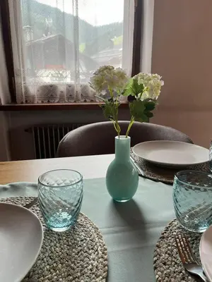 a table with plates and a vase with flowers in it at Ciasa Cianins in San Vigilio Di Marebbe