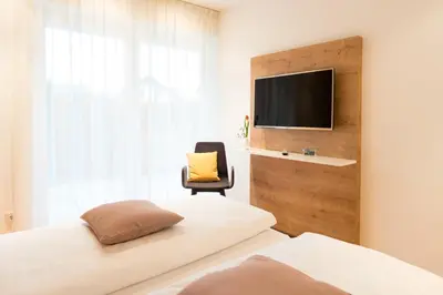 a bedroom with two beds and a tv and a chair at Apartment Oberlechner in Riscone