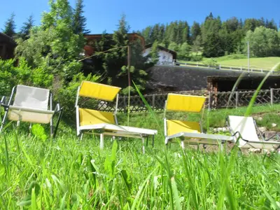a group of three chairs sitting in the grass at Villa Ula Verda- Apartments Marianna in Santa Cristina in Val Gardena