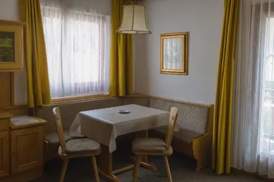 a table and chairs in a room with yellow curtains at Villa Ula Verda- Apartments Marianna in Santa Cristina in Val Gardena