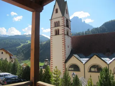 a building with a clock tower with a view at Villa Ula Verda- Apartments Marianna in Santa Cristina in Val Gardena