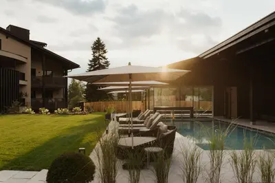 a patio with an umbrella and chairs next to a pool at Waldrast - Forestside Living in Siusi