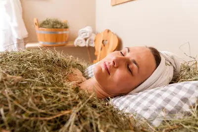 a woman laying in a pile of hay at Hotel Heubad in Fiè