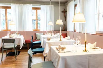 a dining room with four tables and chairs and windows at Hotel Heubad in Fiè