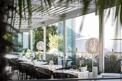 a restaurant with tables and chairs and windows at Small & Beautiful Hotel Gnaid in Tirolo