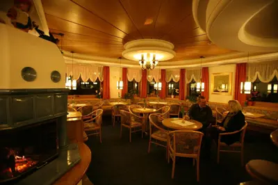 a restaurant with two people sitting at tables and a fireplace at Hotel Bellavista in Canazei