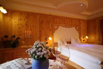 a bedroom with a bed and a table with flowers at Hotel Bellavista in Canazei