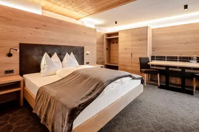 a bedroom with a bed and a desk and a table at Garni Charlotte in Selva di Val Gardena