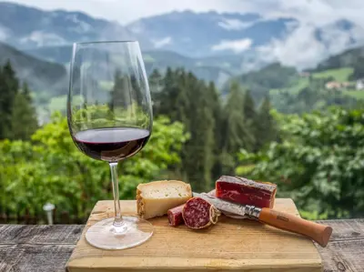 a glass of wine and cheese on a cutting board at Natur Apartments Riesen in San Lorenzo di Sebato