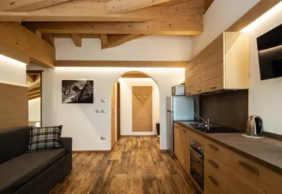 a kitchen with wooden flooring and a living room at San Martino Mountain Residence in San Martino di Castrozza