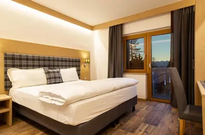 a hotel room with a bed and a window at San Martino Mountain Residence in San Martino di Castrozza