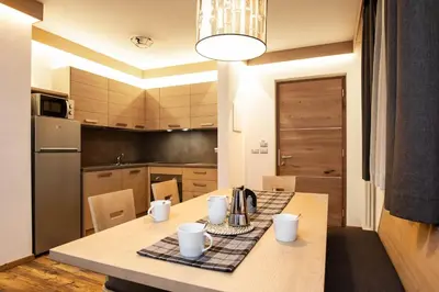 a kitchen with a wooden table with a table cloth at San Martino Mountain Residence in San Martino di Castrozza