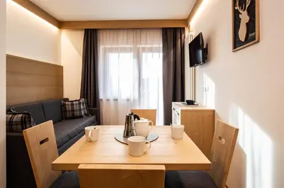 a room with a table with cups and a couch at San Martino Mountain Residence in San Martino di Castrozza
