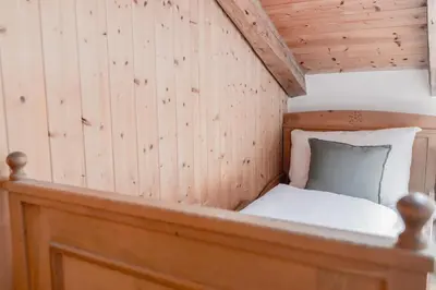 a small bed in a room with wooden walls at Chalet Hafling Zoila in Avelengo