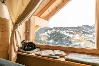 a window seat with books and a view of a mountain at agriturismo Lüch Picedac in La Valle