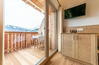 a room with a balcony with a table and a television at agriturismo Lüch Picedac in La Valle