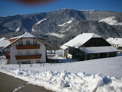 a house in the snow with mountains in the background at Holzerhof Lothen , Campolino in San Lorenzo di Sebato