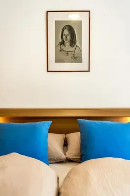 a bed with blue pillows and a picture on the wall at Holzerhof Lothen , Campolino in San Lorenzo di Sebato
