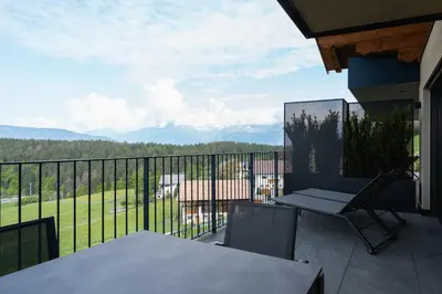 a balcony with a table and a chair and mountains at Beim Lackl in Avelengo