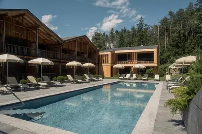 a hotel with a swimming pool with chairs and umbrellas at Dolomites Nature Hotel Vigilerhof in Siusi