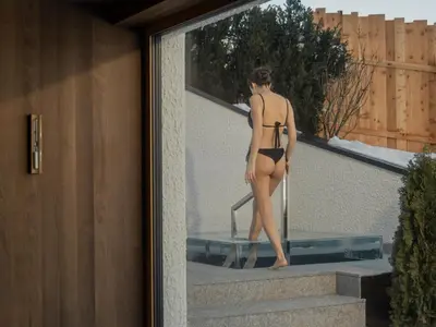 a woman in a bathing suit standing in a mirror at Dolomites Nature Hotel Vigilerhof in Siusi