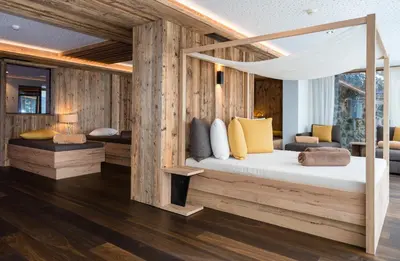 a bedroom with a canopy bed with wooden walls at Dolomites Nature Hotel Vigilerhof in Siusi