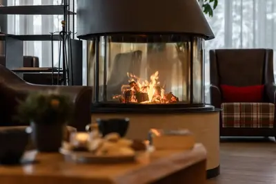 a fire in a fireplace in a living room at Dolomites Nature Hotel Vigilerhof in Siusi