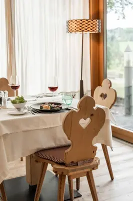 a table with a plate of food and glasses of wine at Dolomites Nature Hotel Vigilerhof in Siusi