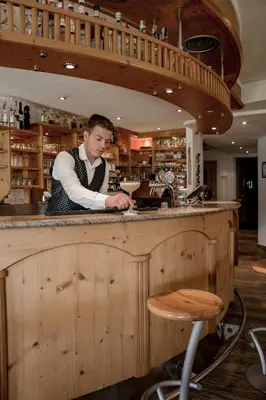 a man standing at a counter in a bar at Dolomites Nature Hotel Vigilerhof in Siusi