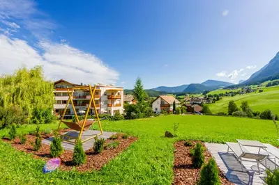 a playground in a yard with a house in the background at Hotel Castel Oswald von Wolkenstein in Castelrotto