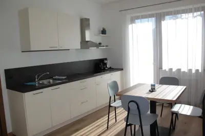 a kitchen with white cabinets and a table with chairs at Residence die Färbe in Vipiteno